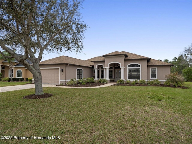 mediterranean / spanish-style home featuring an attached garage, driveway, a front yard, and stucco siding