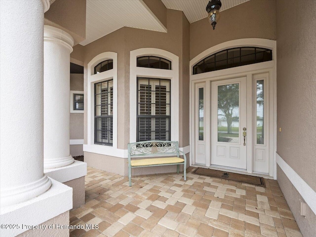 view of exterior entry with a porch and stucco siding