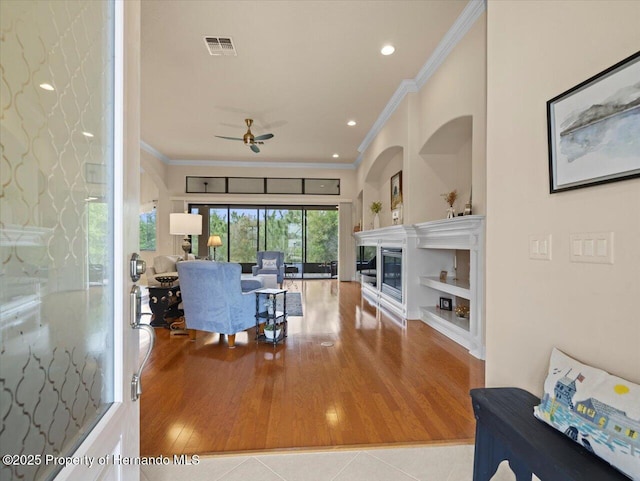 living room featuring visible vents, a glass covered fireplace, ornamental molding, tile patterned flooring, and recessed lighting