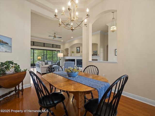 dining space featuring ornamental molding, a fireplace, wood finished floors, and baseboards