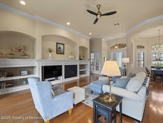 living area with ceiling fan with notable chandelier, visible vents, wood finished floors, and recessed lighting