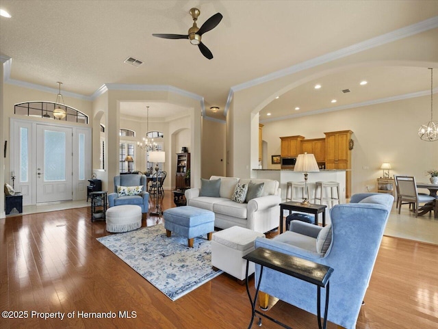 living area featuring ceiling fan with notable chandelier, visible vents, recessed lighting, and wood finished floors