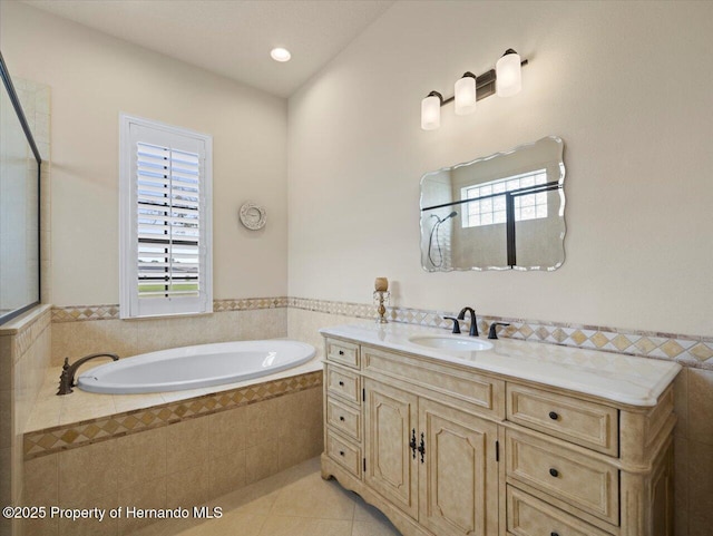 bathroom with tile patterned flooring, a wainscoted wall, a garden tub, and vanity