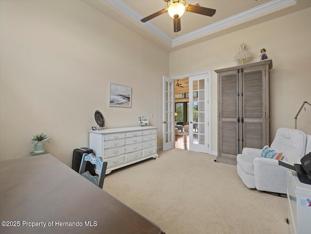 bedroom with a ceiling fan, french doors, a tray ceiling, carpet, and crown molding