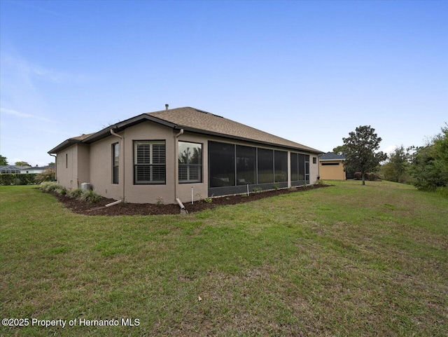 rear view of property featuring stucco siding, a sunroom, and a yard