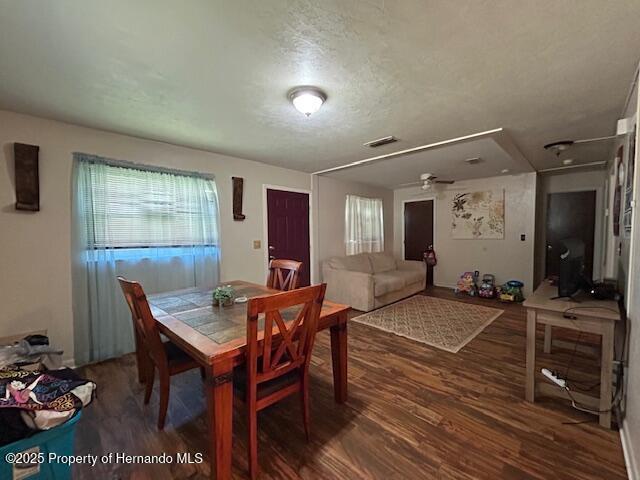 dining room featuring a textured ceiling, wood finished floors, and visible vents