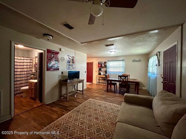 living room with ceiling fan, wood finished floors, and visible vents