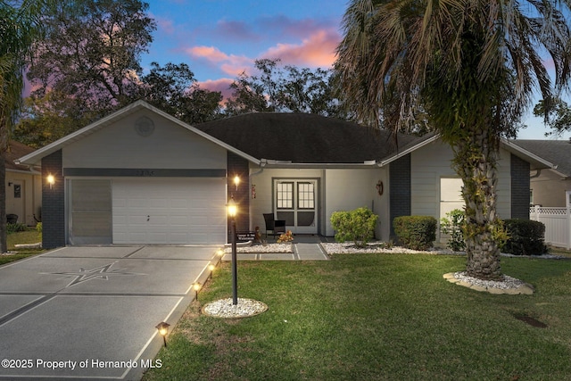 ranch-style home featuring fence, concrete driveway, a front yard, an attached garage, and brick siding