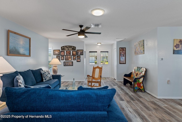 living area featuring visible vents, wood finished floors, french doors, baseboards, and ceiling fan