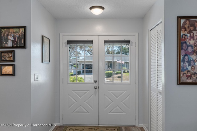 doorway featuring wood finished floors, french doors, baseboards, and a textured ceiling