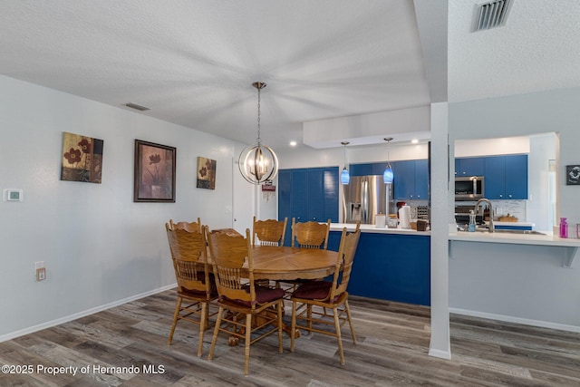 dining space with baseboards, dark wood-style floors, visible vents, and a textured ceiling