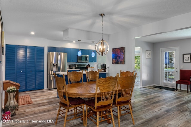 dining room featuring an inviting chandelier, baseboards, light wood finished floors, and a textured ceiling