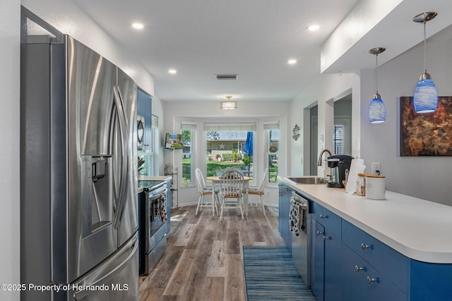 kitchen featuring blue cabinets, stainless steel appliances, dark wood-style flooring, and a sink