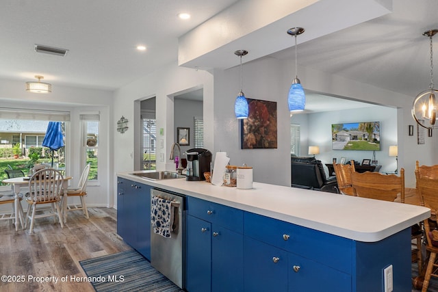 kitchen with visible vents, blue cabinetry, stainless steel dishwasher, wood finished floors, and a sink