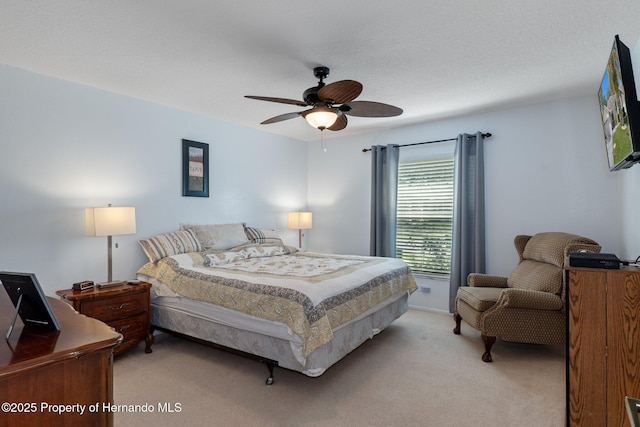 bedroom featuring a ceiling fan, light colored carpet, and a textured ceiling