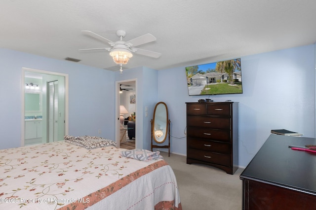 bedroom featuring ceiling fan, visible vents, ensuite bathroom, and light carpet