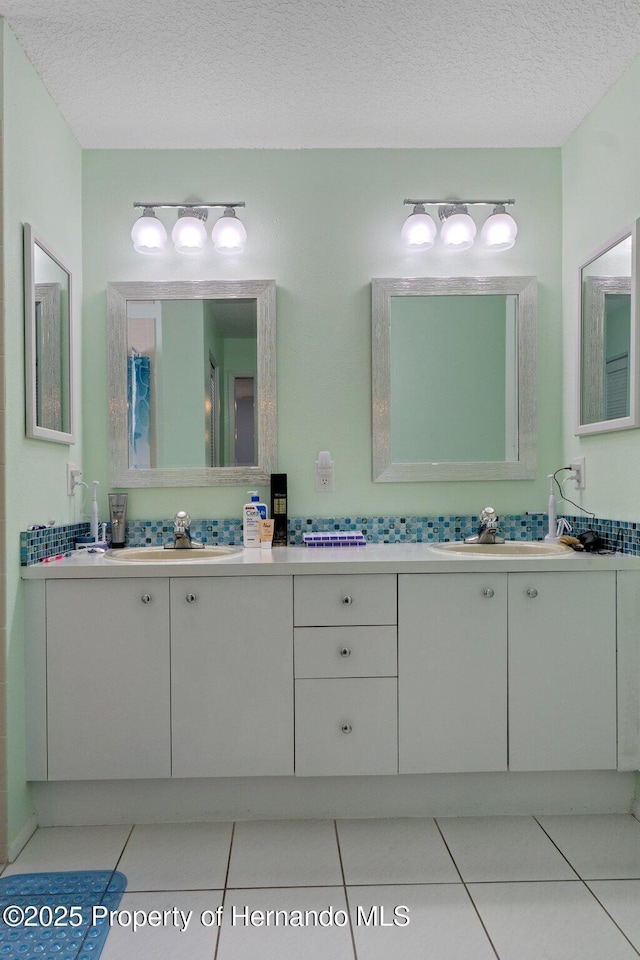 bathroom featuring a textured ceiling, double vanity, tile patterned flooring, and a sink