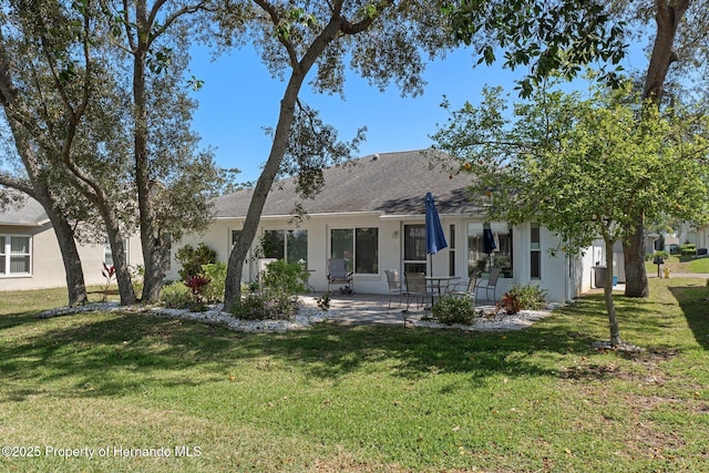 back of property featuring stucco siding, a patio, and a yard