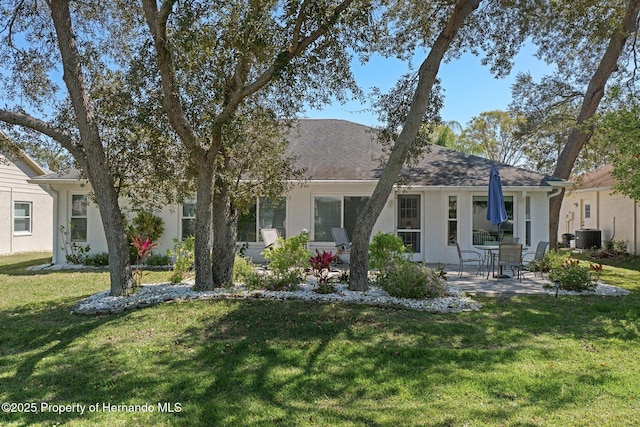 view of front facade featuring a front lawn, a patio area, central AC, and stucco siding