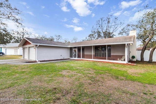 ranch-style home with aphalt driveway, a garage, a sunroom, a front lawn, and a chimney