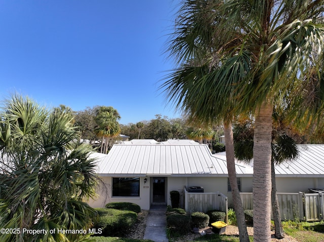 view of front of home featuring stucco siding, metal roof, and fence