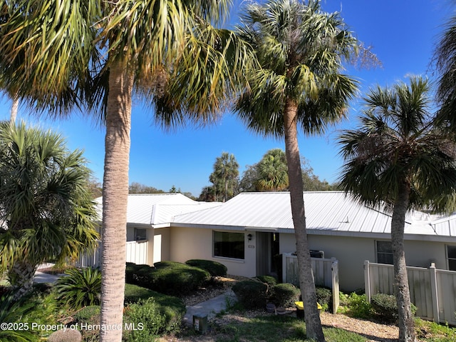 view of front of property with stucco siding, metal roof, and fence