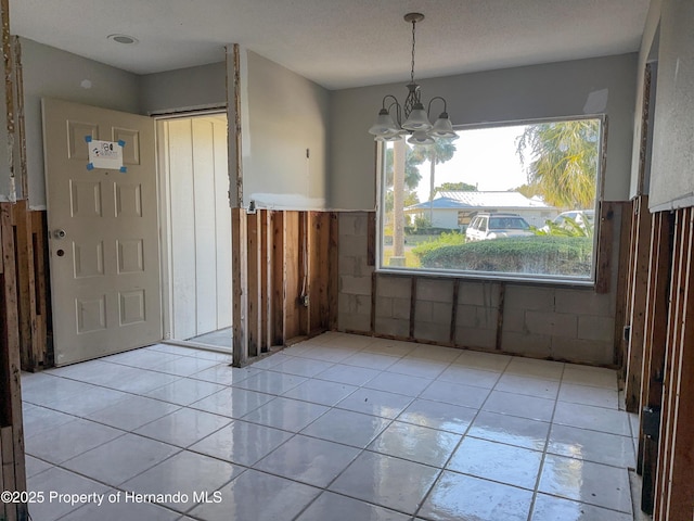 unfurnished dining area featuring light tile patterned flooring and a chandelier