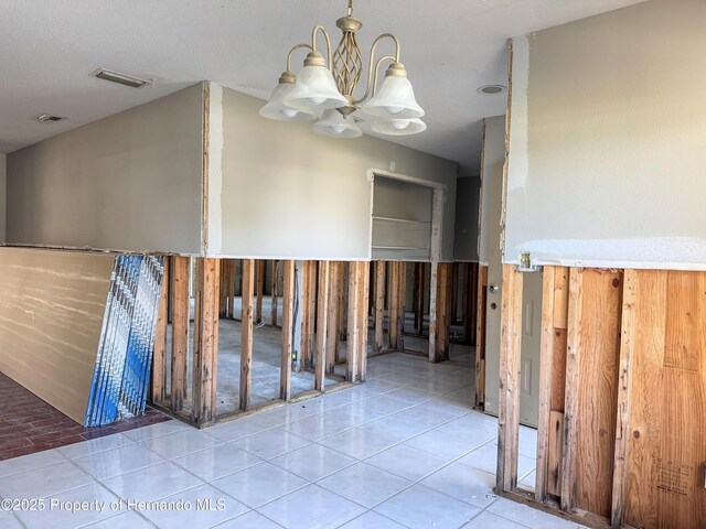 hallway featuring tile patterned floors, visible vents, and a chandelier