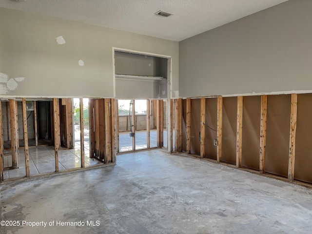 misc room featuring visible vents, a textured ceiling, and unfinished concrete flooring