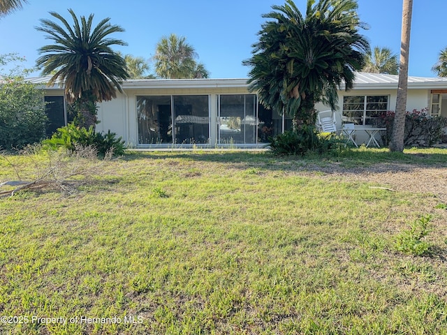 back of property featuring stucco siding, a lawn, and a sunroom