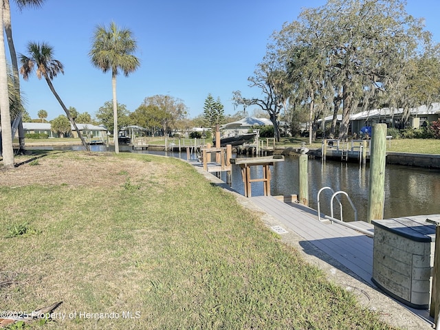 view of dock with a water view and a lawn