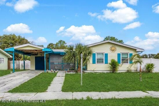 ranch-style house featuring a front yard, concrete driveway, fence, and an attached carport