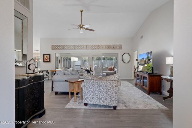 living area with wood finished floors, visible vents, baseboards, high vaulted ceiling, and ceiling fan