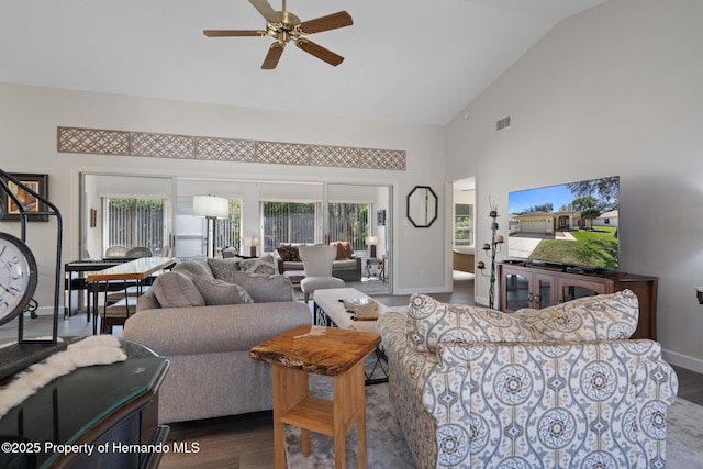 living area featuring visible vents, ceiling fan, baseboards, wood finished floors, and high vaulted ceiling