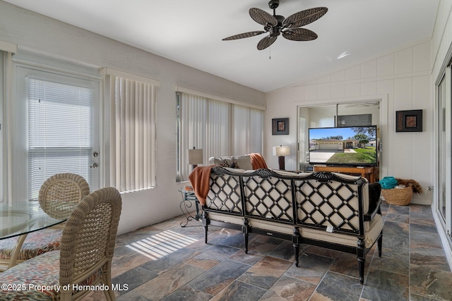 interior space with stone tile flooring, a ceiling fan, and vaulted ceiling