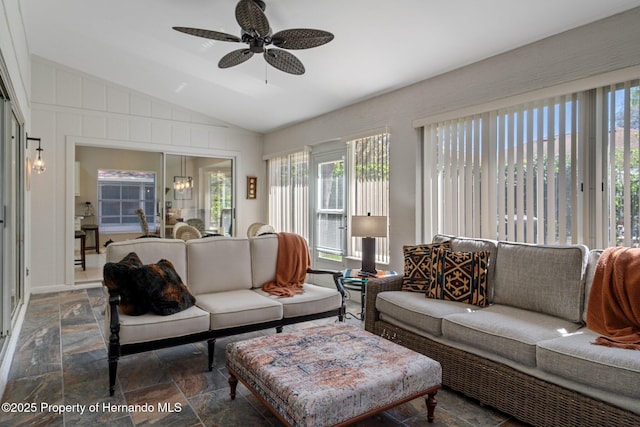 living room featuring stone finish flooring, lofted ceiling, and a ceiling fan