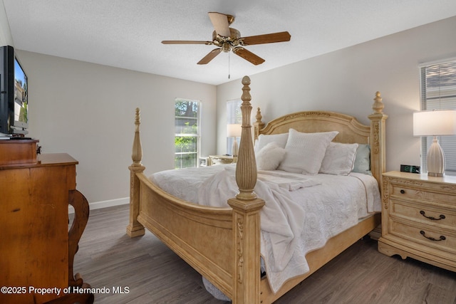 bedroom featuring ceiling fan, a textured ceiling, dark wood-type flooring, and baseboards