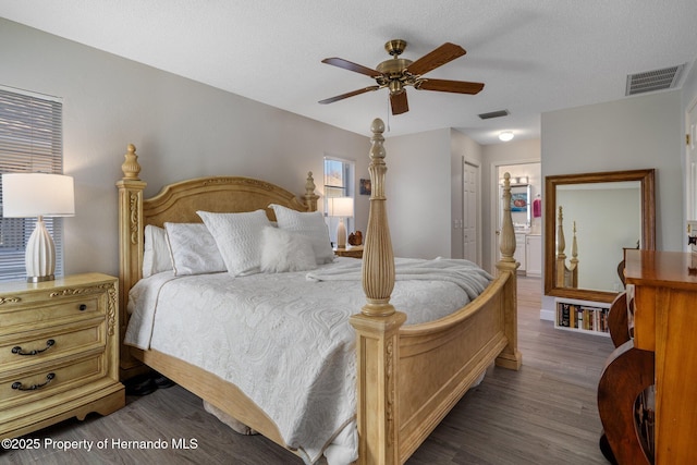 bedroom featuring visible vents, dark wood-style floors, and a ceiling fan