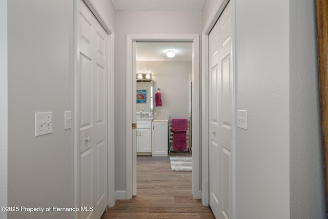 hall featuring a textured ceiling and wood finished floors