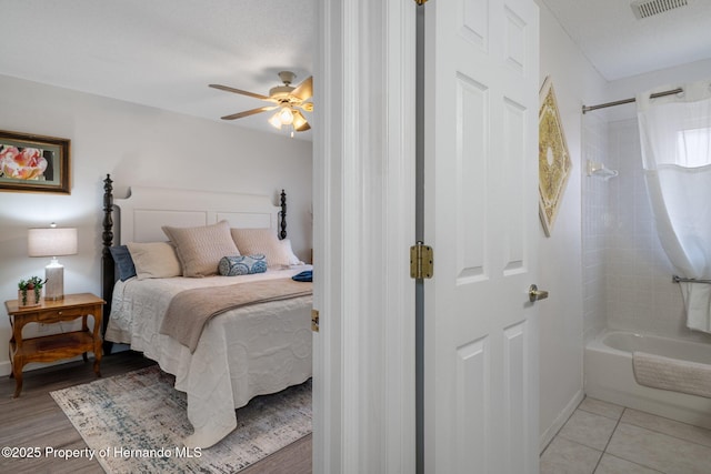 bedroom featuring light tile patterned floors, baseboards, visible vents, and ceiling fan