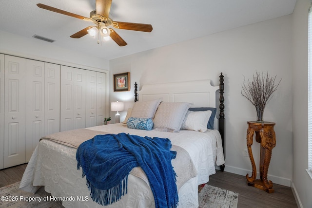 bedroom featuring wood finished floors, visible vents, baseboards, ceiling fan, and a closet