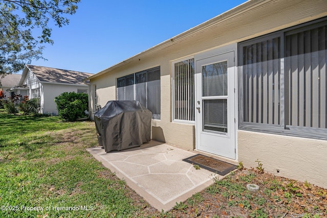 exterior space featuring stucco siding, a lawn, and a patio area