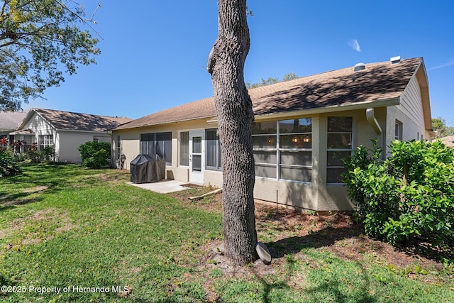 rear view of house with a lawn and stucco siding