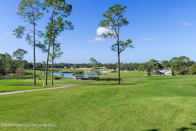 view of property's community with golf course view, a lawn, and a water view