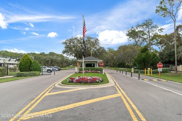 view of road with traffic signs, street lights, and a gated entry