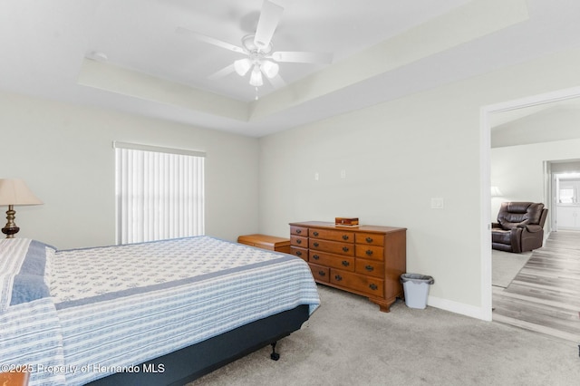 bedroom featuring ceiling fan, baseboards, a raised ceiling, and carpet flooring