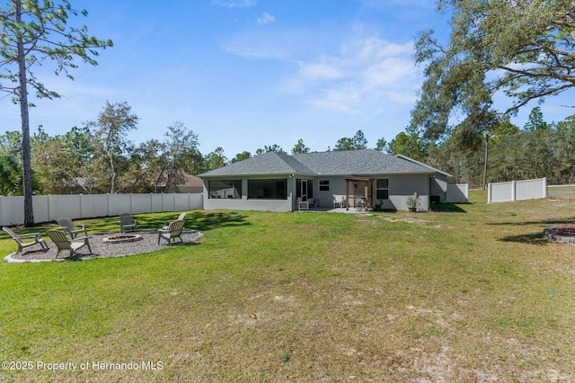 rear view of house featuring a yard, stucco siding, a sunroom, a fenced backyard, and a fire pit