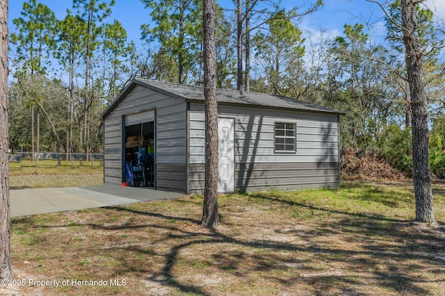 view of outbuilding with driveway, fence, and an outdoor structure