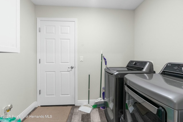 washroom with laundry area, washer and clothes dryer, baseboards, and wood finished floors