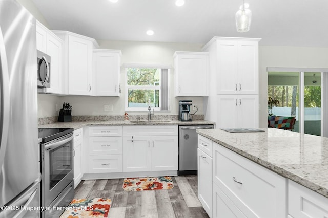 kitchen featuring stainless steel appliances, light wood finished floors, a sink, and white cabinets